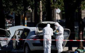 Members of the scientific police inspect a burned car at the scene of an incident in which a car rammed a gendarmerie van on the Champs-Elysees Avenue in Paris