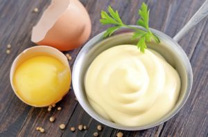 mayonnaise in metal spoon on wooden board