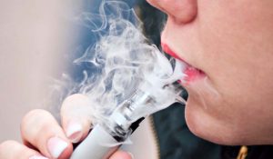 Closeup of mouth of woman with e-cigarette in outdoor